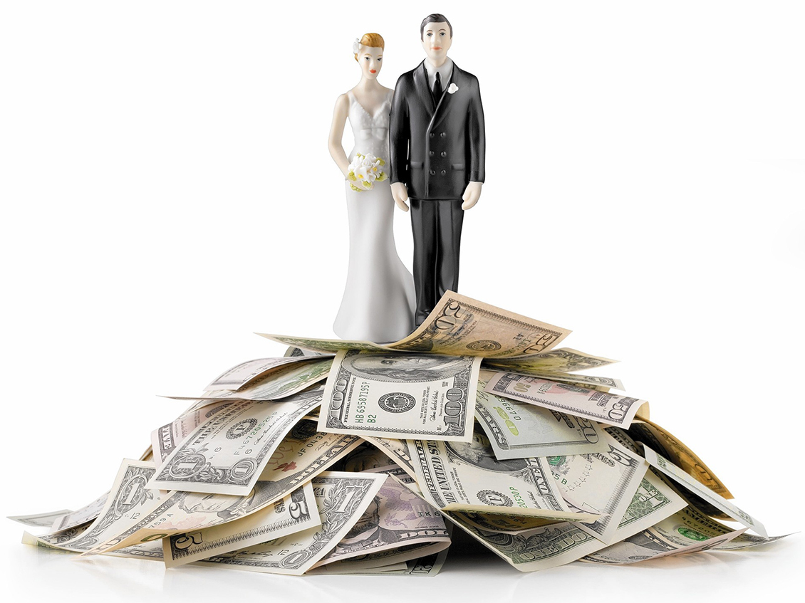 bride and groom cake toppers on a pile of cash
