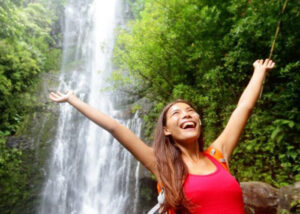 happy women traveler in the forest by the waterfall